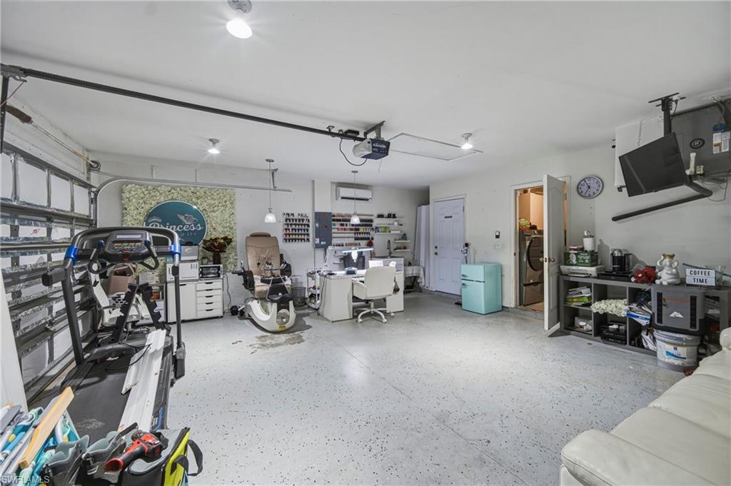 Finished garage space featuring a speckled epoxy floor, overhead lighting, and a roll-up garage door
