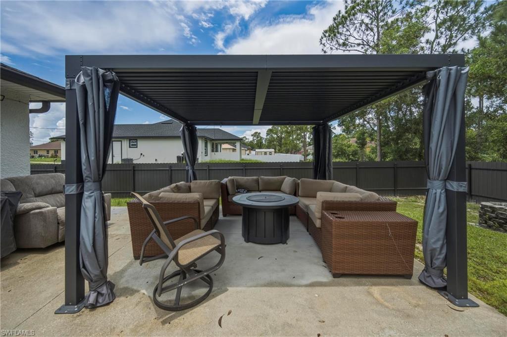 Paved patio featuring a black louvered pergola with retractable privacy screens