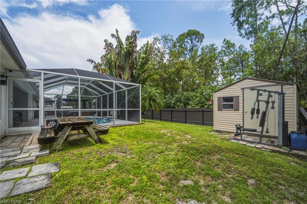 Expansive rear yard featuring a screened-in pool enclosure, a storage shed, and a privacy fence