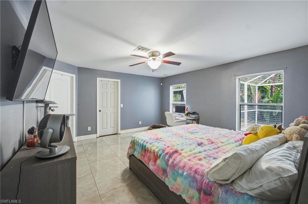 Spacious room featuring neutral tile flooring, light gray walls, and multiple windows with white blinds