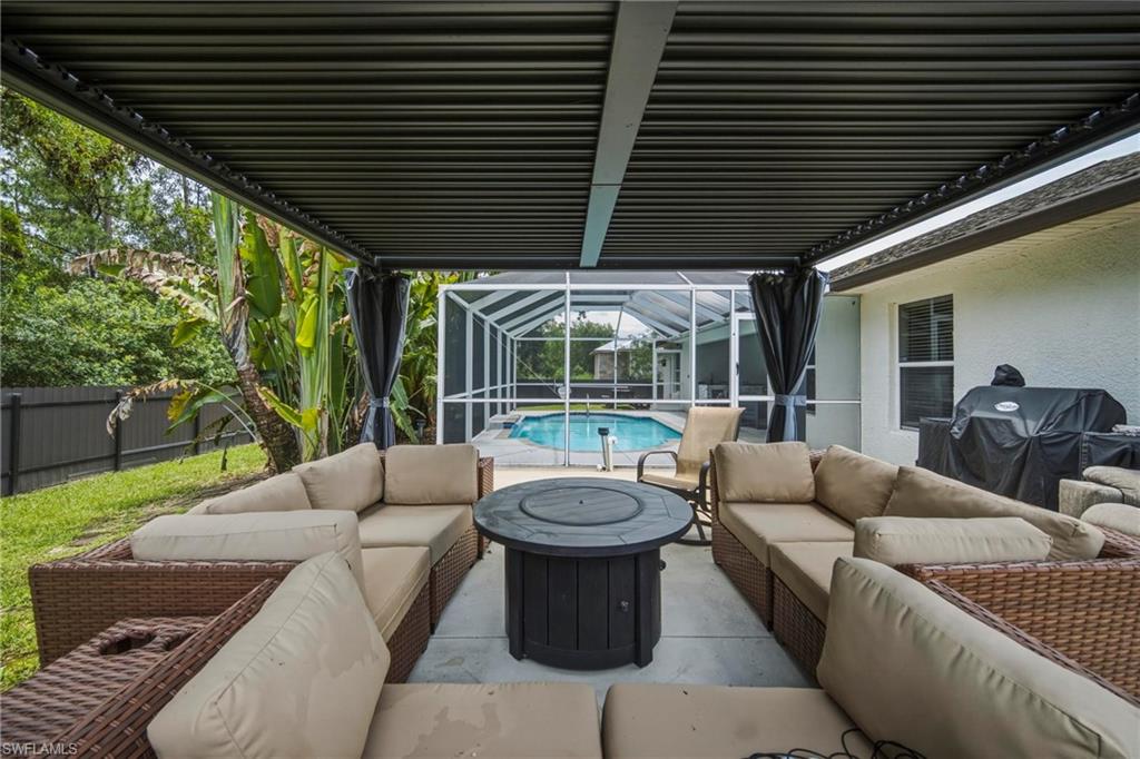 Covered patio space featuring a screened-in swimming pool, a privacy fence, and mature tropical landscaping