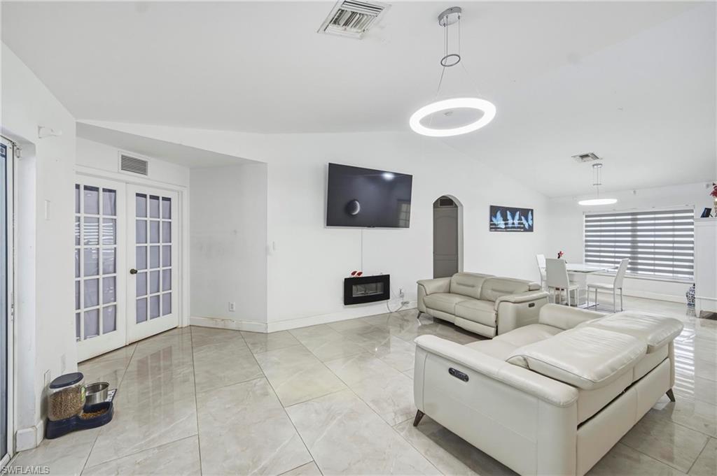 Spacious interior featuring large format tile flooring, vaulted ceilings, and a modern wall-mounted electric fireplace