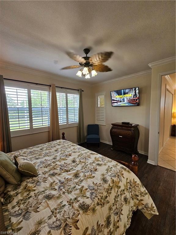 Bedroom featuring dark wood-style flooring, a textured ceiling, a ceiling fan, and crown molding