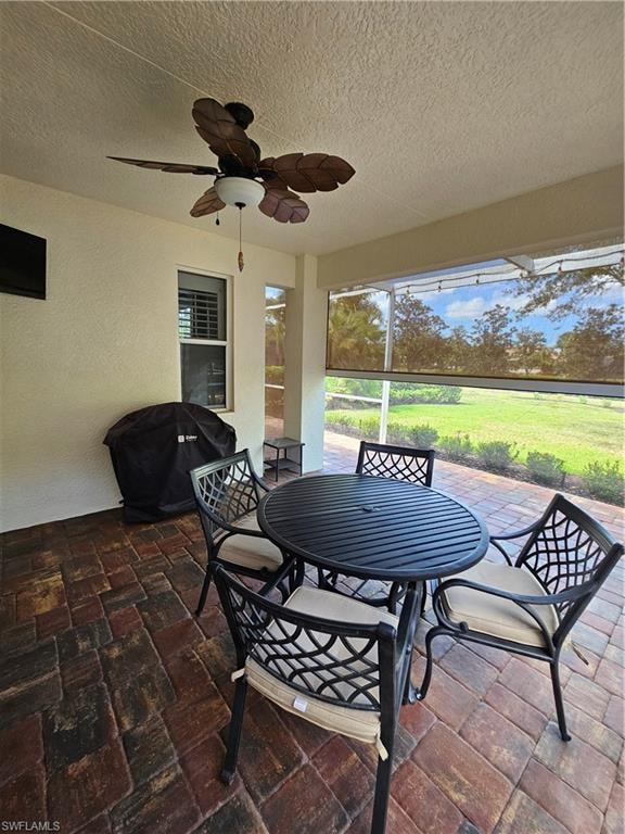 View of patio featuring area for grilling, ceiling fan, a sunroom, and outdoor dining area