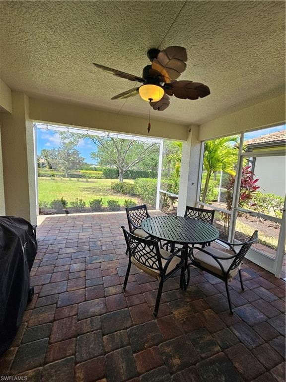 Sunroom / solarium featuring outdoor dining area and a ceiling fan