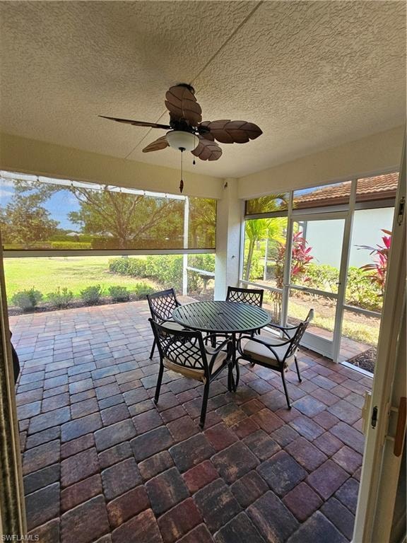 Sunroom featuring ceiling fan and outdoor dining space