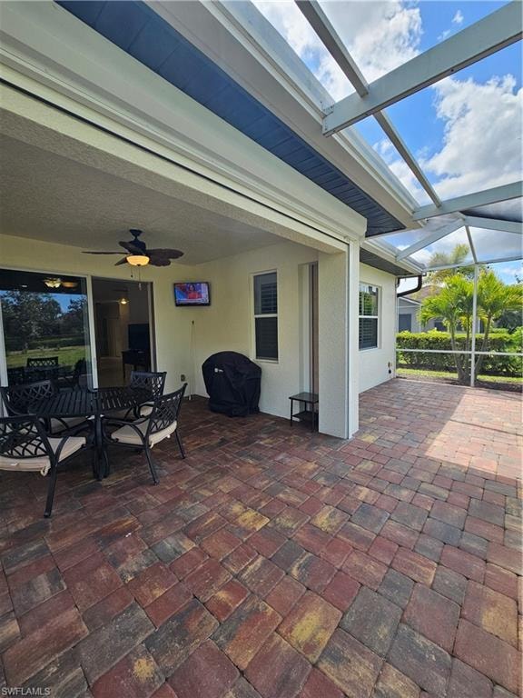 View of patio with a sunroom, outdoor dining space, ceiling fan, a lanai, and a grill