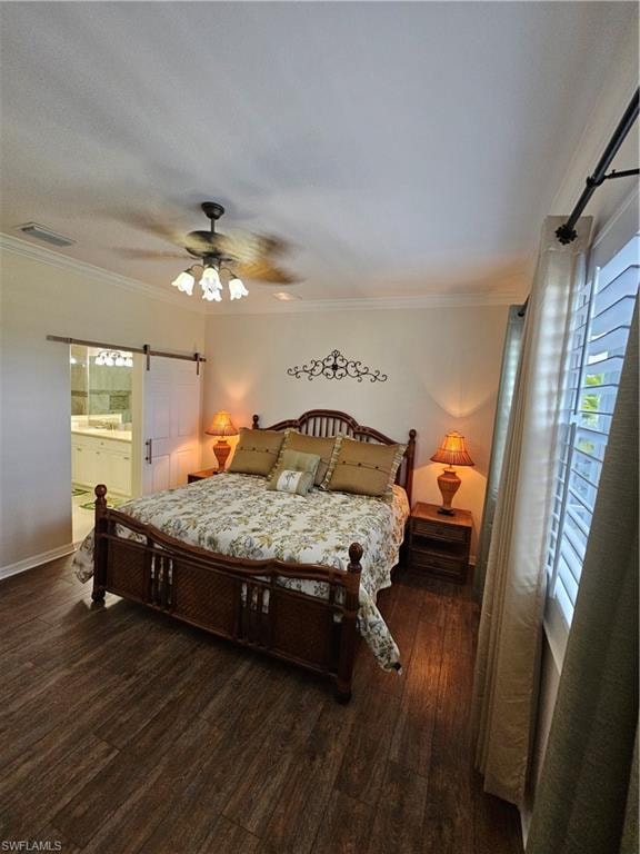 Bedroom featuring a barn door, dark wood-style flooring, a ceiling fan, ornamental molding, and ensuite bath