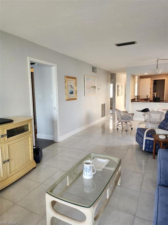 Open-concept living area featuring light-toned tile flooring, neutral wall paint, and white trim