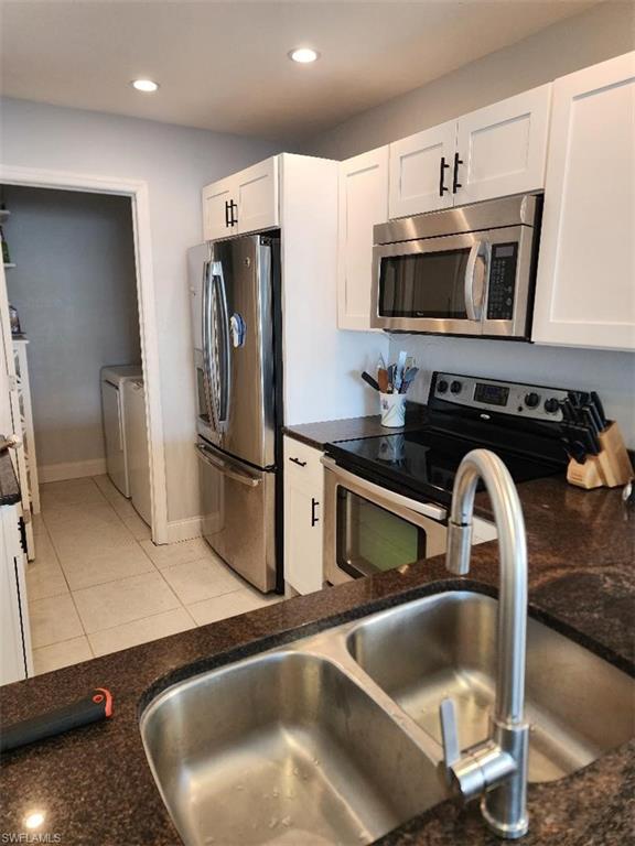 Kitchen featuring a double stainless steel sink with a gooseneck faucet, brown speckled countertops, and white shaker-style cabinetry with black hardware