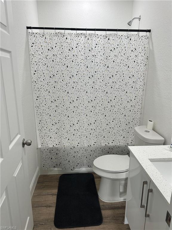 Full bathroom featuring a shower-over-tub combination with a chrome showerhead, a white toilet, and a white vanity with a light-colored countertop