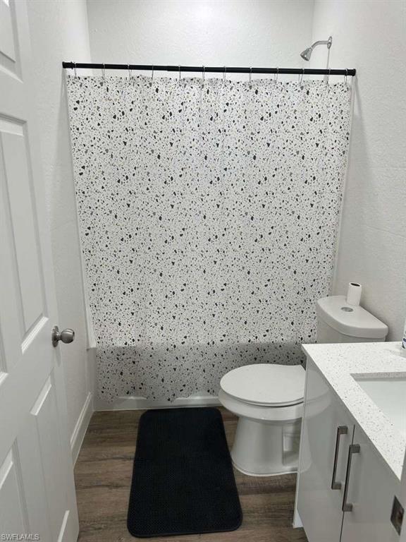 Bathroom featuring wood-finish flooring, a white vanity with a light-colored countertop, and a white toilet