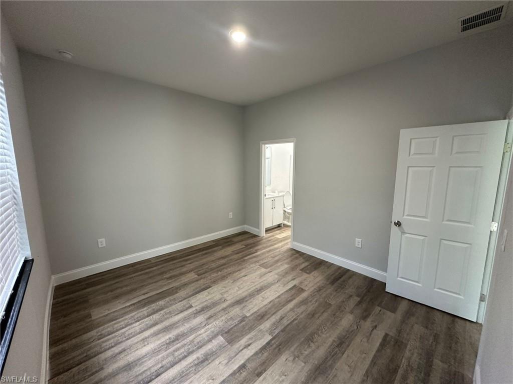 Spacious room featuring wood-finish flooring, light grey painted walls, white trim, and recessed lighting