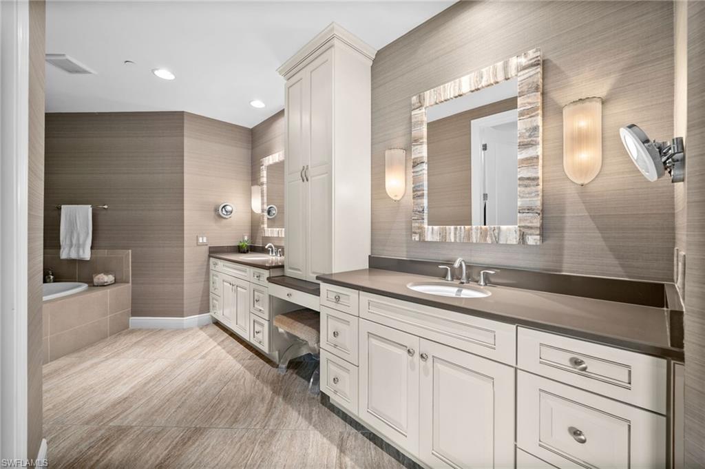 Full bath featuring two vanities, tiled tub, and recessed lighting