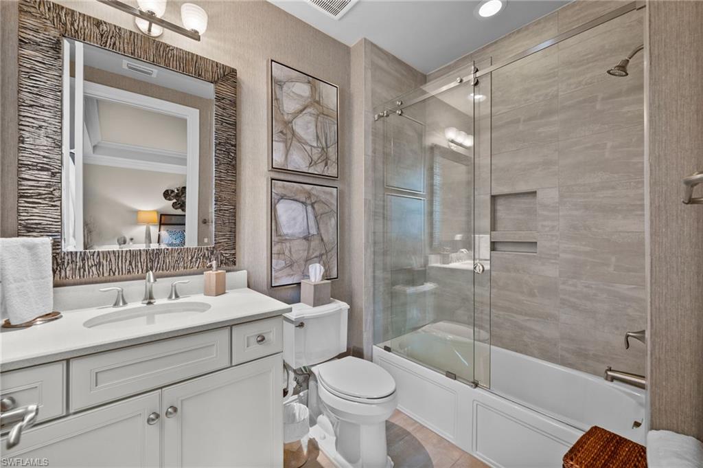 Bathroom with shower / bath combination with glass door, vanity, and radiator