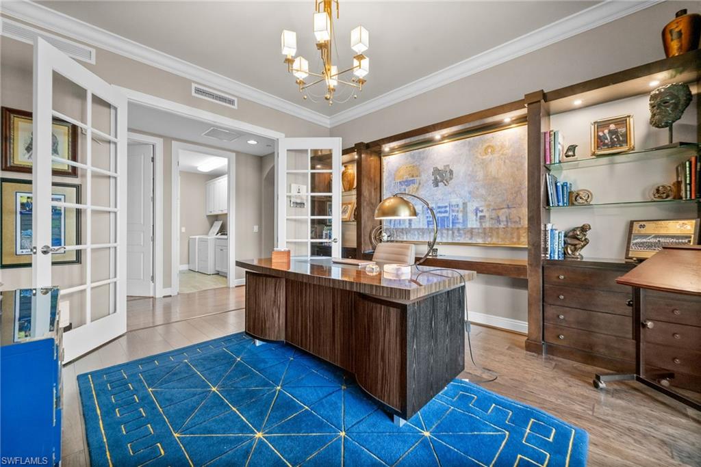 Home office featuring light wood-style floors, ornamental molding, french doors, and a chandelier