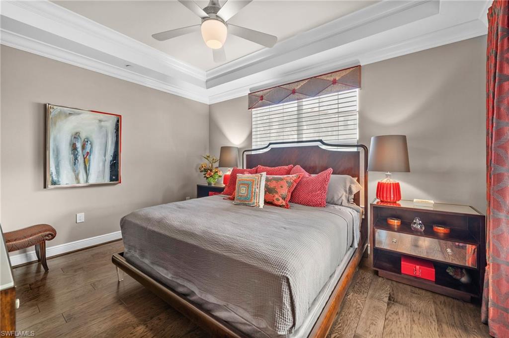 Bedroom with a tray ceiling, hardwood / wood-style floors, ornamental molding, and ceiling fan