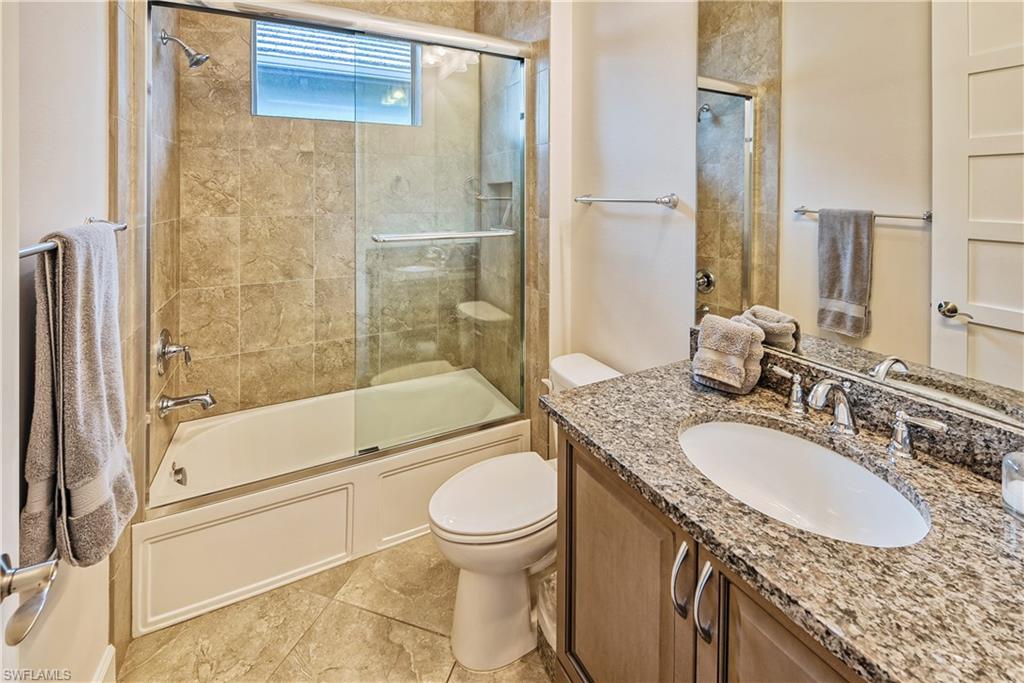 Full bathroom with shower / bath combination with glass door, vanity, and toilet