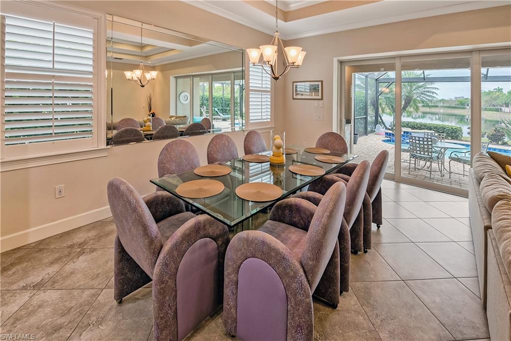 Dining area with a chandelier, light tile patterned floors, a tray ceiling, and ornamental molding
