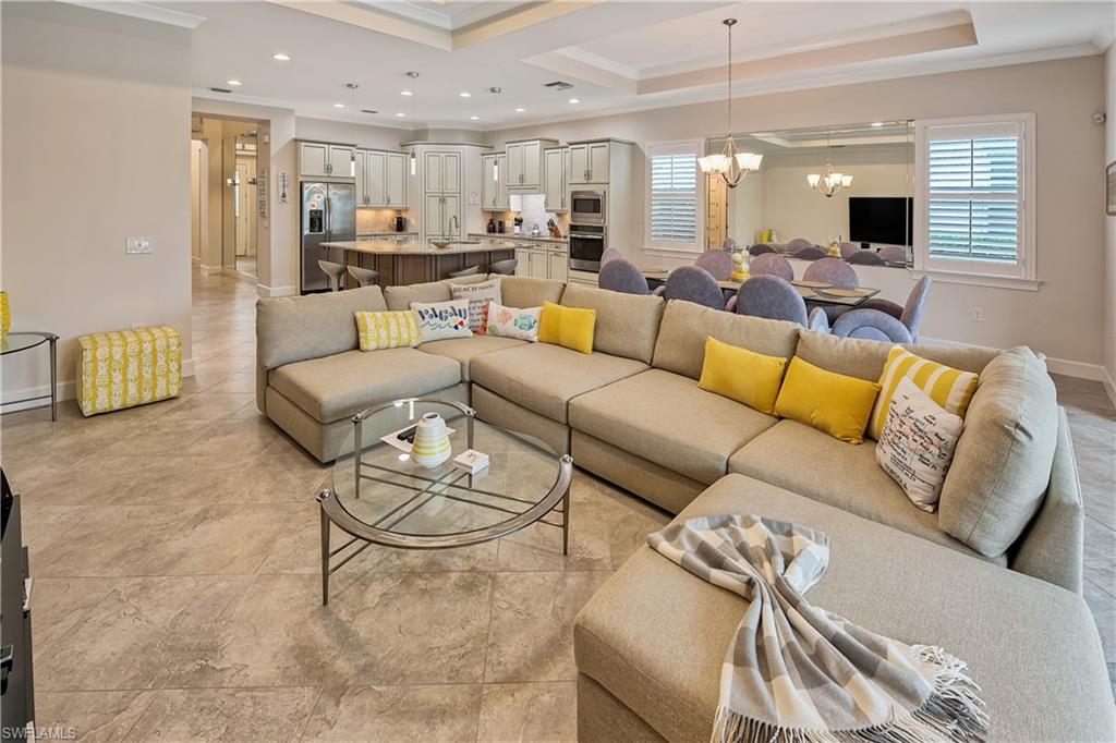 Living room with a notable chandelier, a raised ceiling, ornamental molding, and sink