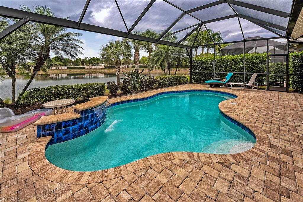 View of pool with pool water feature, glass enclosure, a water view, and a patio