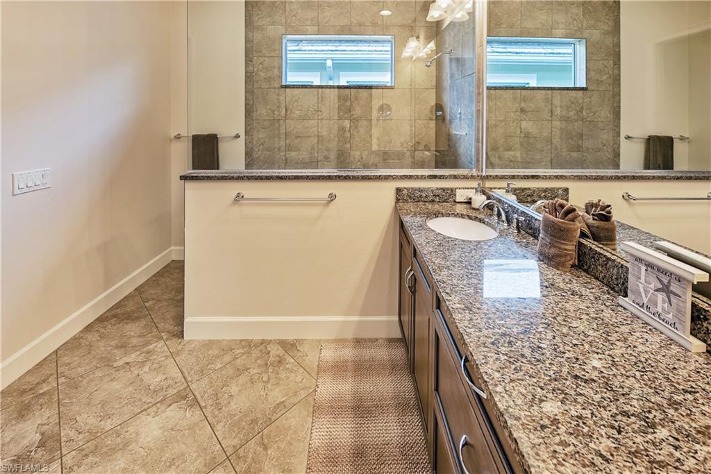 Bathroom featuring tiled shower, vanity, and a healthy amount of sunlight