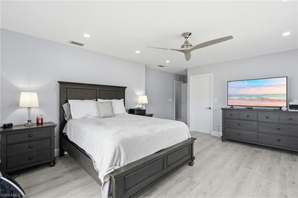 Spacious room featuring light-toned walls and wood-finish flooring