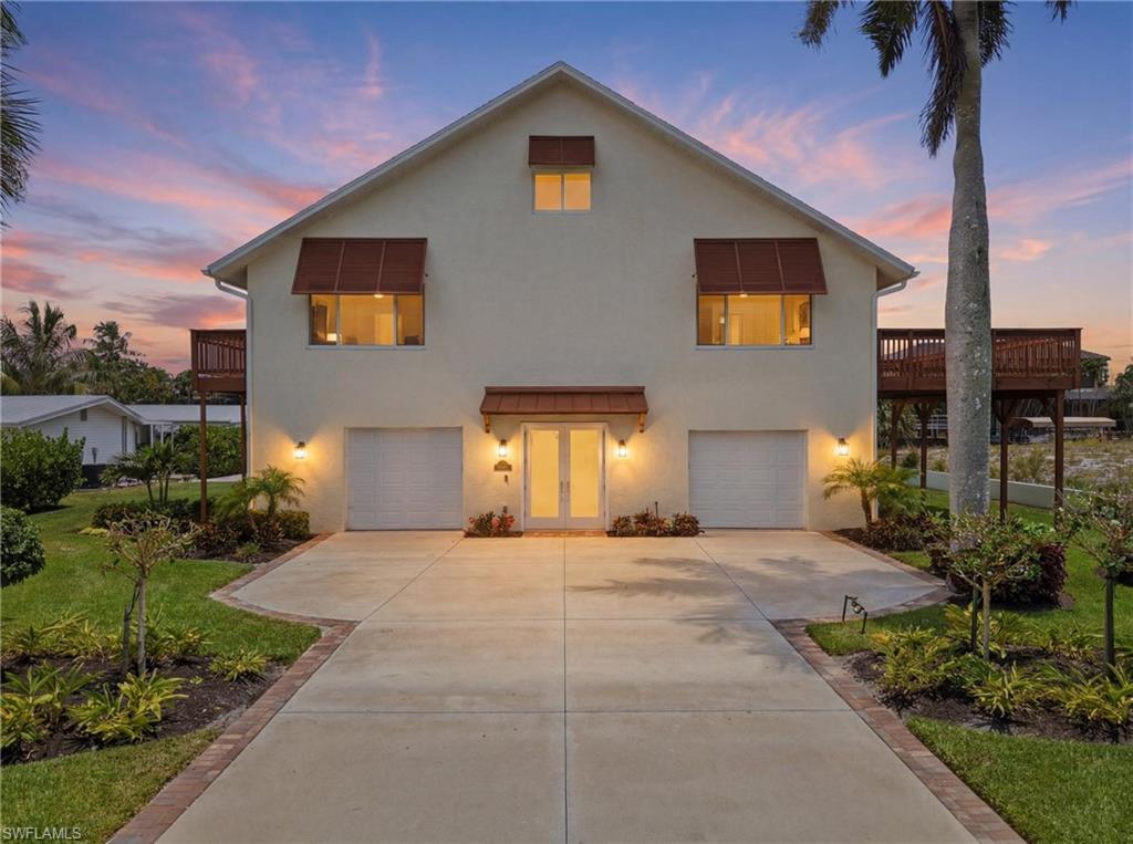 Two-story stucco home featuring a central entry with transom window, two integrated garages, and two elevated wood decks