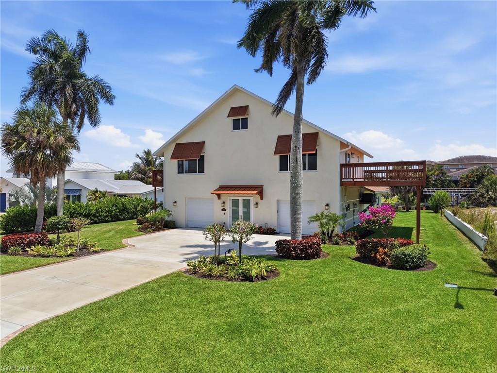 Contemporary multi-level residence featuring a large elevated deck, dual garage doors, and a concrete driveway