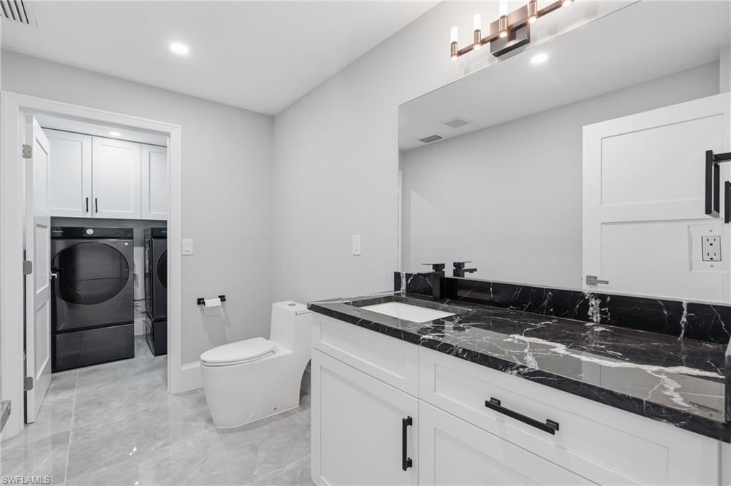 Bathroom featuring a white vanity with black marbled countertop and integrated sink