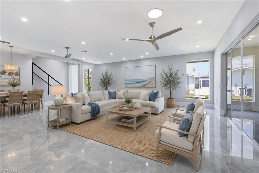 Expansive open-concept living area featuring contemporary ceiling fans, recessed lighting, and large format polished tile flooring