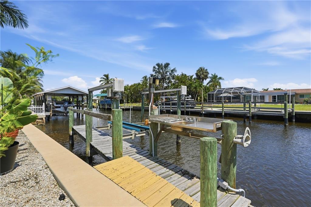 Waterfront property with a private dock featuring a boat lift and a built-in cleaning station