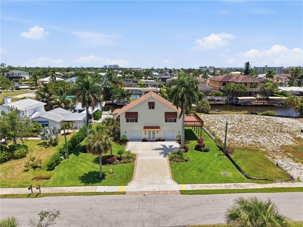 Two-story residence featuring a paved driveway, attached two-car garage, and a waterfront location with an expansive open deck