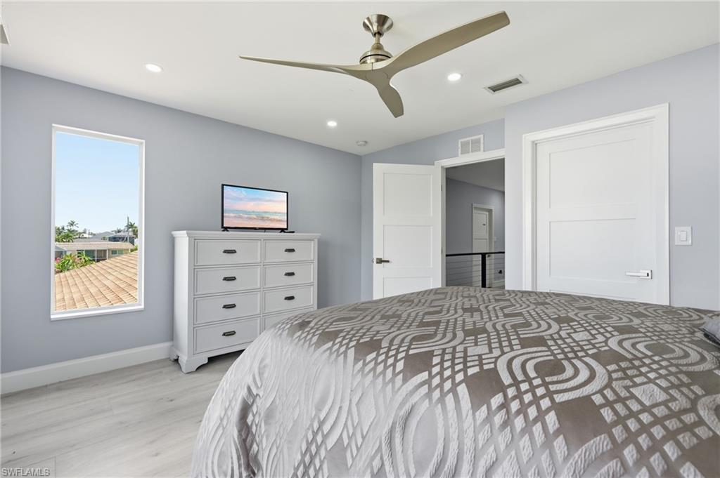 Recessed lighting, a modern ceiling fan, and light wood-finish flooring characterize this room