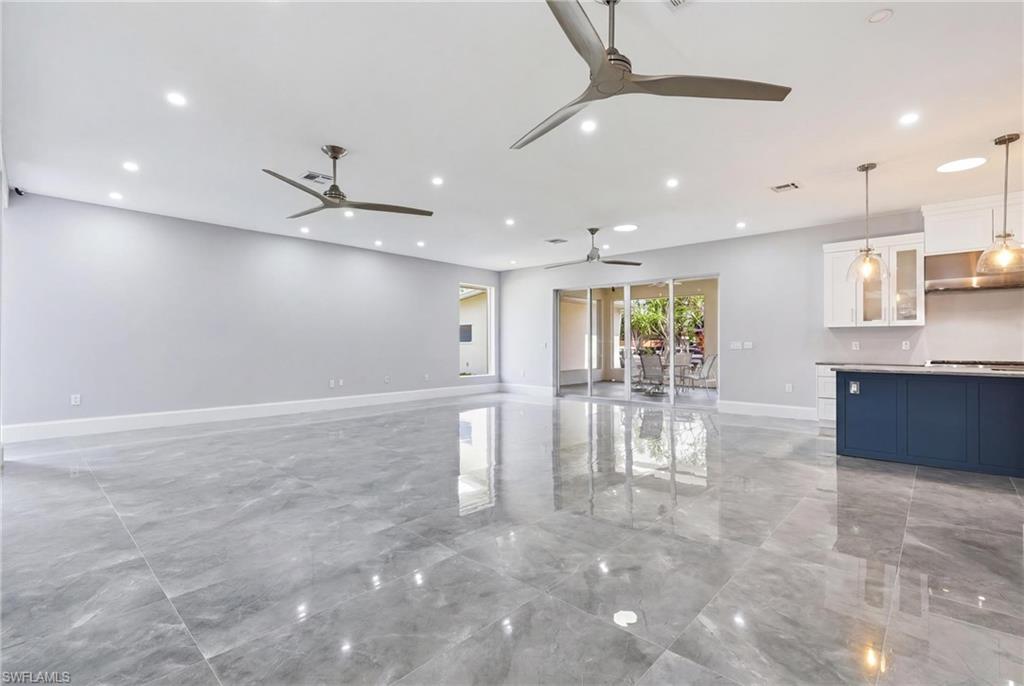 Expansive open-concept living area featuring large format gray tile flooring and recessed lighting