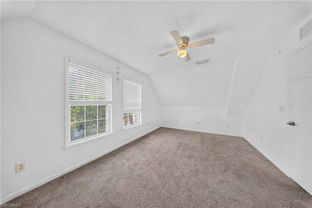 Carpeted room with bright white walls and a sloped ceiling