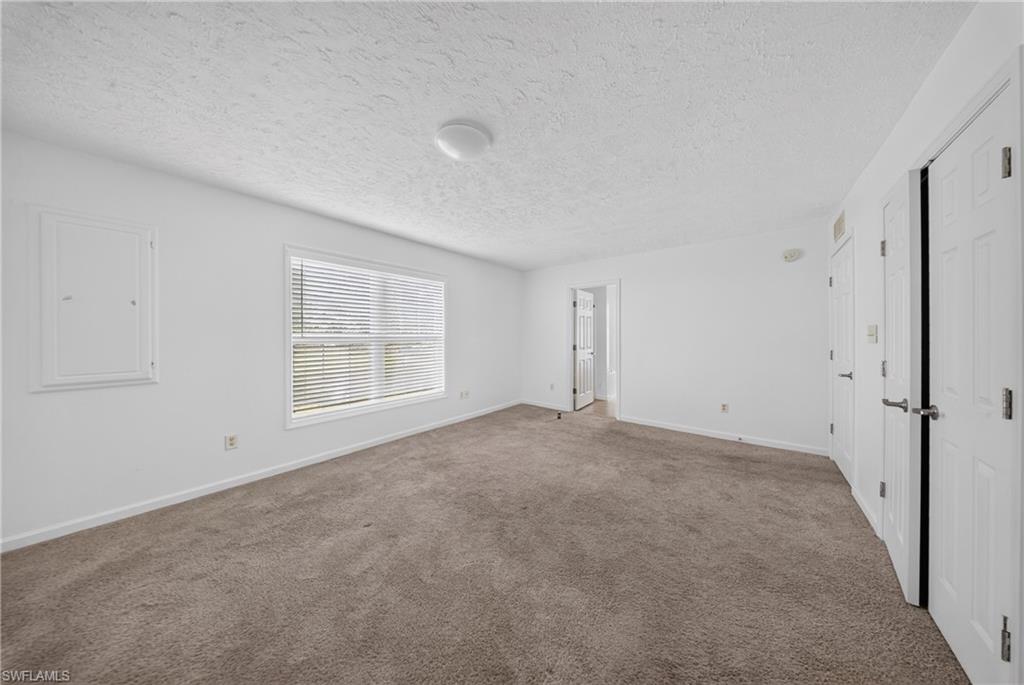 Spacious room featuring neutral carpeting, white walls, and a large window with blinds