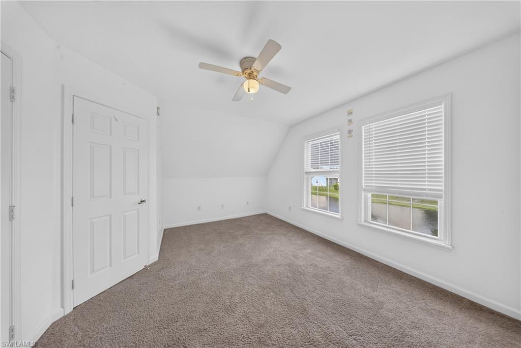 Carpeted room featuring white walls, a sloped ceiling, and two windows with horizontal blinds
