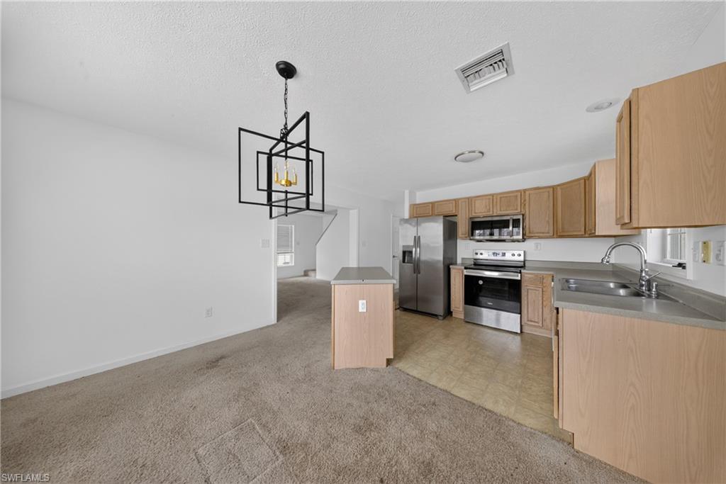 Kitchen area featuring light wood-finish cabinetry and stainless steel appliances