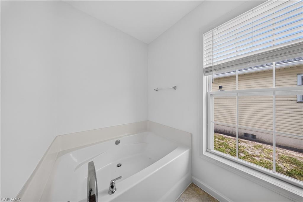 Corner built-in tub featuring integrated jets, polished chrome fixtures, and a surrounding white countertop