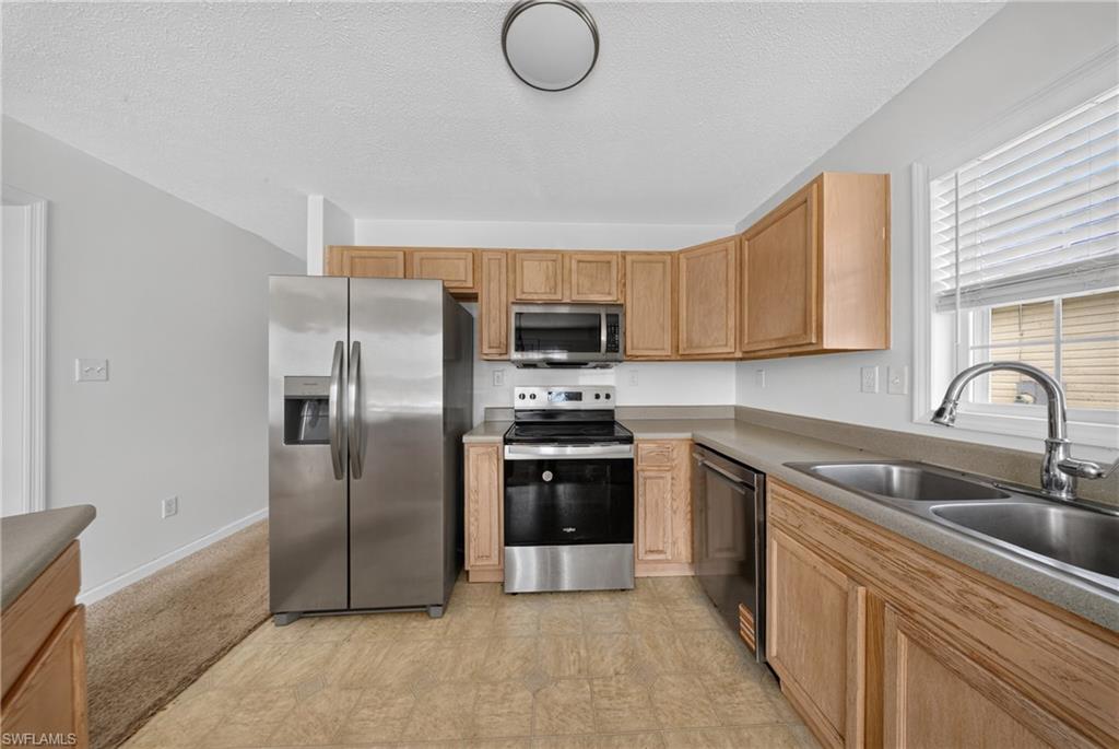 Kitchen with wood-finish cabinetry, stainless steel appliances, and a double basin sink