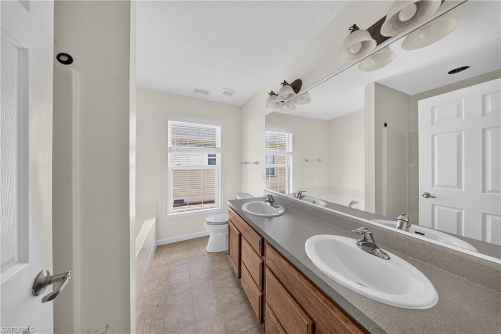 Bathroom featuring a dual vanity with wood-finish cabinetry and a single-piece countertop