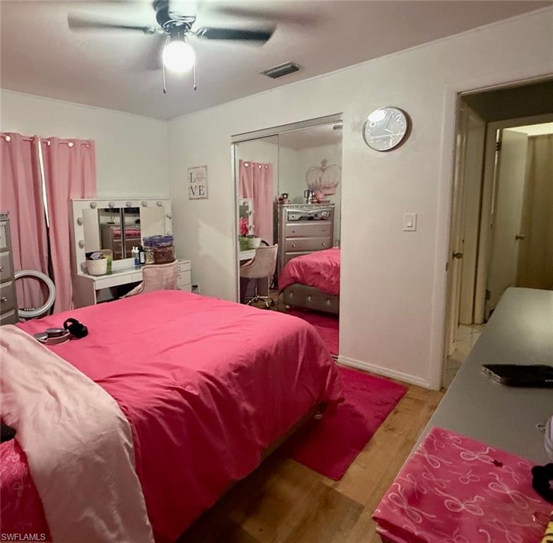Bedroom featuring wood-finish flooring, a ceiling fan with integrated lighting, and a mirrored closet door