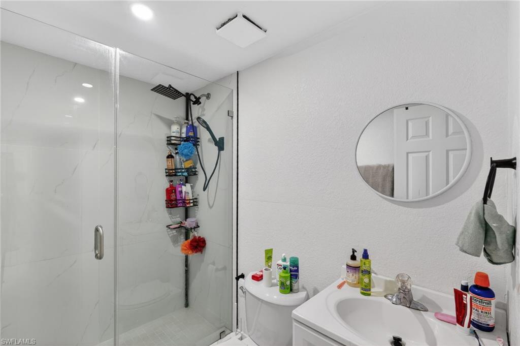 Glass-enclosed shower with white tiled walls and a black rainfall showerhead