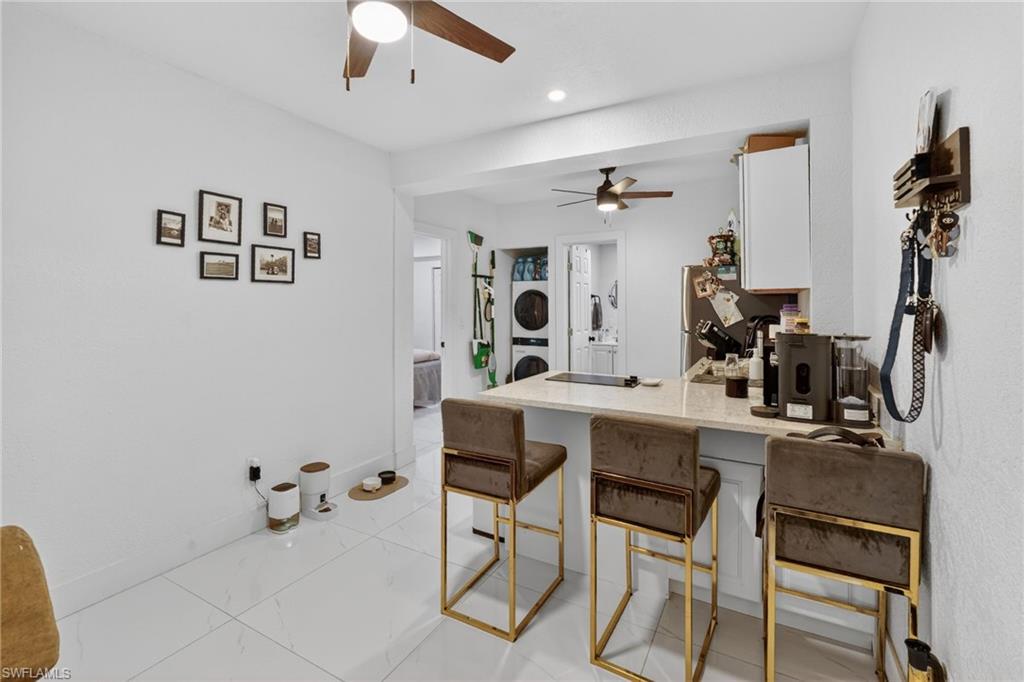 Kitchen bar area featuring a light-toned countertop, white cabinetry, and white tile flooring