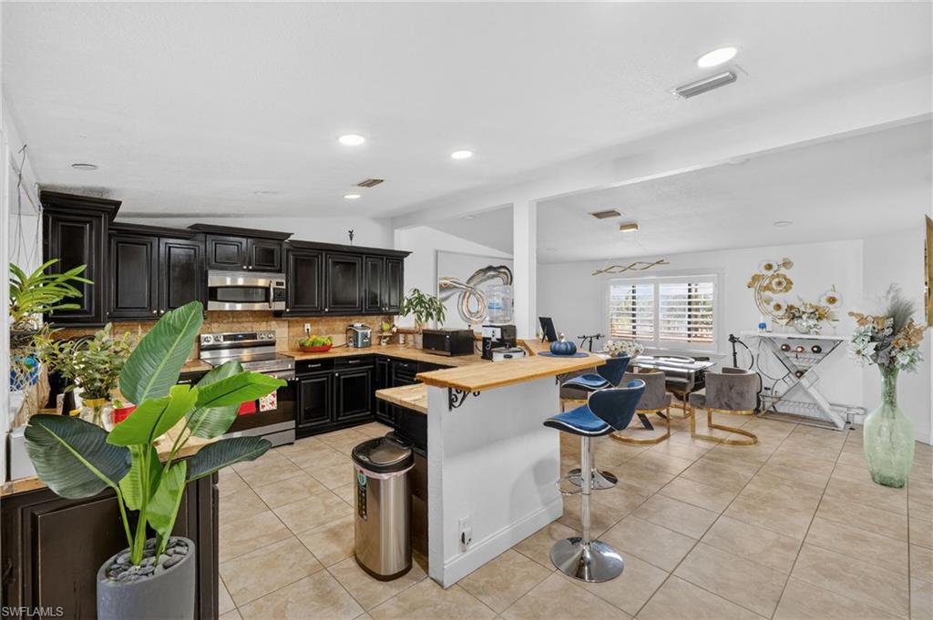Expansive kitchen featuring dark wood cabinetry, stainless steel appliances, and wood-finish countertops