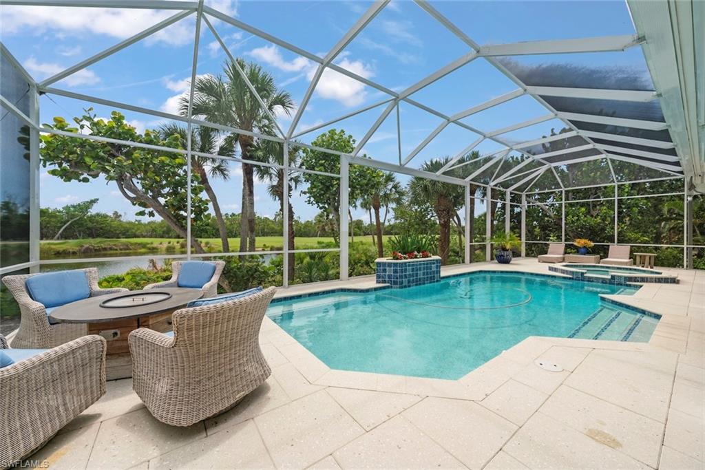 Screened outdoor living area featuring a rectangular pool and integrated spa