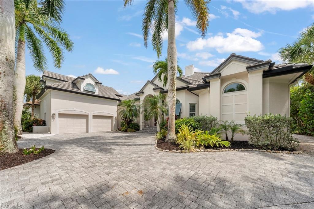 Stucco exterior with a paver driveway, two-car garage, and a tiled roof