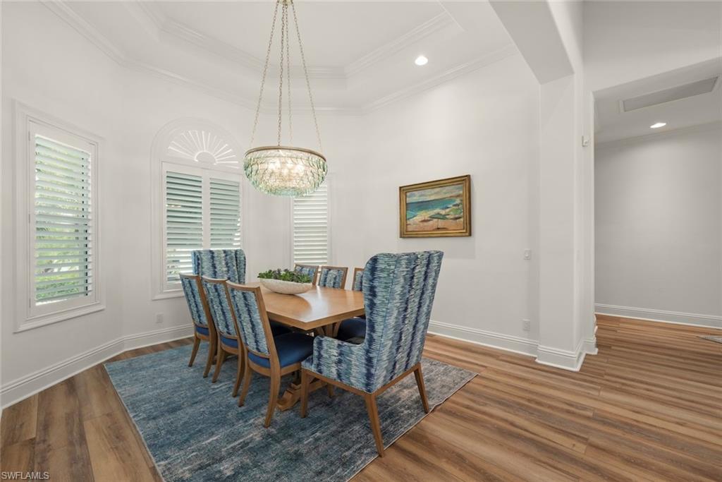 Dining area featuring wood-finish flooring, white plantation shutters, and a coffered ceiling with recessed lighting