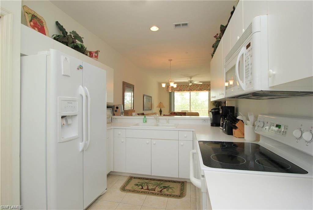 Kitchen with kitchen peninsula, sink, white appliances, and white cabinetry
